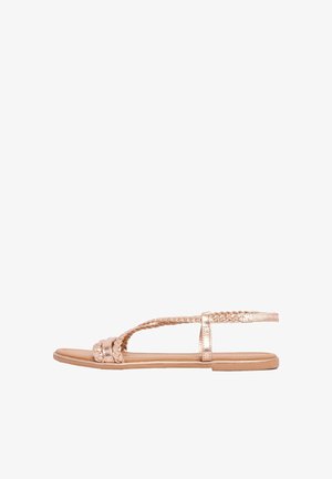Sandalo piatto in oro rosa con cinturini intrecciati e fibbia alla caviglia, design open toe e suola sottile.