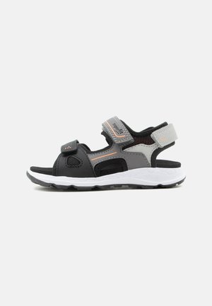 Sandale de sport pour enfant noire, grise et orange avec des sangles réglables et une semelle blanche texturée, montrée de profil sur fond blanc.