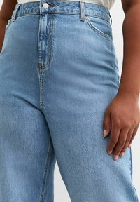 Jeans de talle alto color azul claro, fabricados en denim, con un diseño de pierna recta, costuras visibles y cierre frontal de botón.