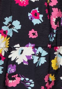 Tissu floral présentant des fleurs multicolores en rose, bleu, violet et jaune sur un fond bleu marine foncé avec une texture.