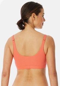 Oranssi ribatut bralette leveillä olkaimilla ja syvällä selkämuotoilulla. Saumatonta reunaa ja pehmeää tekstuuria mukavuutta ja tukea varten.