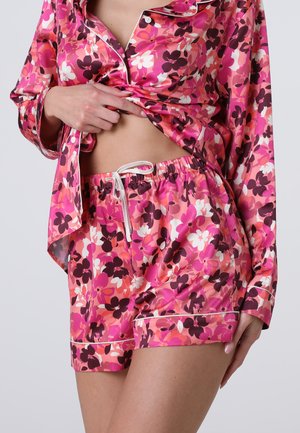 Set da pigiama floreale caratterizzato da tonalità di rosa, viola e bianco. Materiale satinato con vestibilità ampia, camicia con bottone e pantaloni corti con coulisse e dettagli a costine.