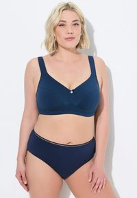 Granatowy biustonosz z szerokimi ramiączkami, dekoltem w kształcie litery V i małą kokardką na środku. Wysokogatunkowe majtki z pasem o teksturowanej fakturze w komplecie.