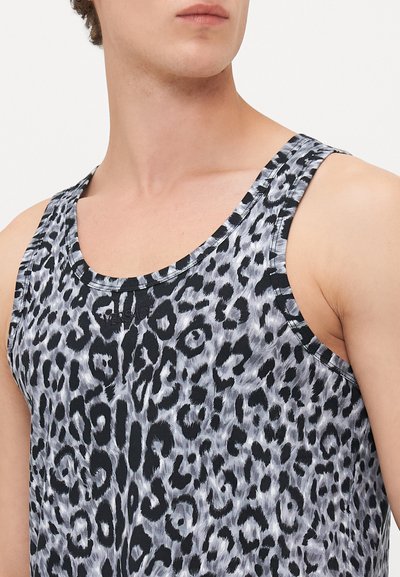Mann trägt ein ärmelloses Tanktop mit einem schwarz-grauen Leopardenmuster, Nahaufnahme auf den Oberkörper und Hals.