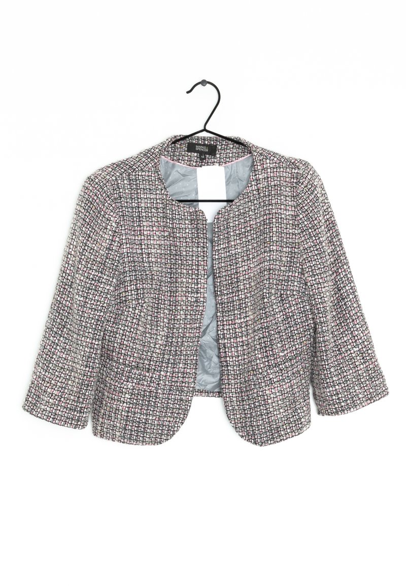 Giacca in tweed testurizzato nei colori nero, bianco e rosa, con una vestibilità corta, scollatura tonda e maniche a tre quarti; appesa a un gancio nero.