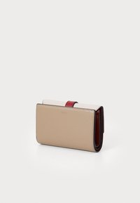Beige och röd läderplånbok med en vikbar design, som har en slät yta och en kontrasterande accentband. Kompakt och rektangulär form.