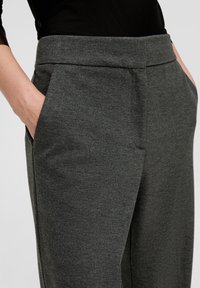 Gray tailored pants made from textured fabric, featuring side pockets and a flat waistband design. The color is consistent throughout.
