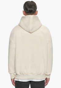Cremfarbene Kapuzenpullover mit lässiger Passform, gerippten Bündchen und Saum. Weicher Stoff, minimalistisches Design und eine großzügige Kapuze.