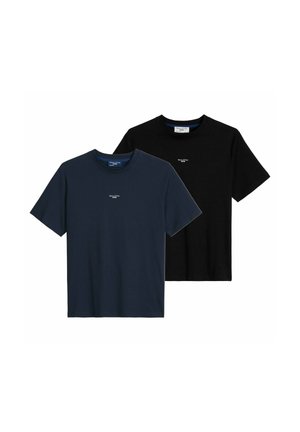 Homme portant un t-shirt noir Marc O’Polo Denim légèrement rentré dans un jean bleu clair, mains dans les poches, cadré au niveau du cou et des cuisses.