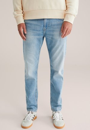 Lichtblauwe denim jeans met een rechte snit, licht vervaagde textuur en standaard vijf-pocket ontwerp, gecombineerd met witte en groene sneakers.