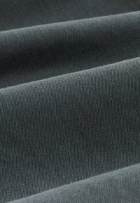 Tela gris oscuro con una superficie suave y texturizada, que muestra un tejido liso y un sutil brillo en las capas dobladas.