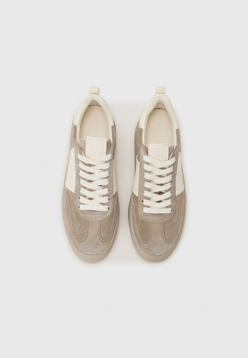 Sneaker mit einem leichten Design aus beigem Wildleder und cremefarbenen Akzenten. Ausgestattet mit flachen Schnürsenkeln, einem Logodetail auf der Zunge und einer strukturierten Sohle.