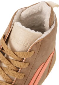 Sapatilhas de camurça bege com forro em lã macia na cor bege, detalhes laterais laranja e atacadores beje. Projetadas com uma forma arredondada e superfície texturizada.