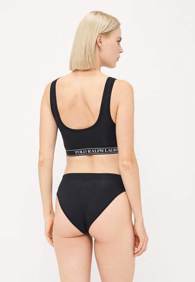 Ensemble en tissu lisse composé d'un soutien-gorge noir et d'une culotte taille haute. Le soutien-gorge présente des bretelles larges et une bande logo ; la culotte a un design sans coutures.