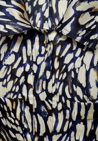 Overhemd met knoopsluiting, gemaakt van lichtgewicht stof en voorzien van een gedurfd, abstract patroon in marineblauw, blauw en wit met kleine oranje accenten, en een opgestikte zak.