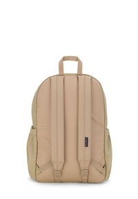 Sac à dos beige de forme arrondie, avec un dos et des bretelles rembourrés, deux poches latérales, et une poignée sur le dessus pour un transport facile.