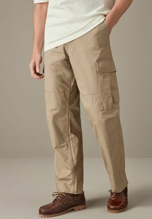 Pantaloni cargo bej dintr-un material ușor, cu buzunare laterale, croială dreaptă și o textură ușor șifonată. Asortați cu pantofi maroon.