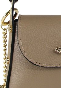 Sac à main en cuir beige avec une finition texturée, un rabat arrondi, des accessoires en métal doré et une bandoulière en chaîne amovible pour plus de polyvalence.