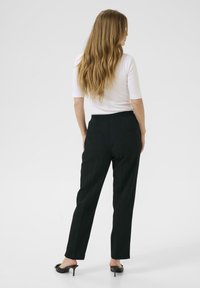 Schwarze, taillierte Hosen mit geradem Schnitt, elastischem Bund und Rückentasche. Getragen mit einem taillierten, weißen Oberteil mit Dreiviertelärmeln.