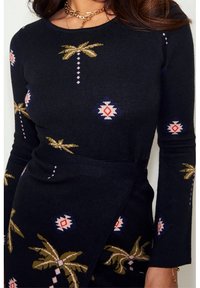 Schwarzer Pullover mit langen Ärmeln, der Palmen- und geometrische Muster in Grün, Pink und Blau zeigt. Strukturierte Strickmaterial, taillierte Passform.