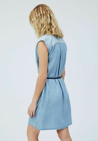 Light blue denim dress with short sleeves, lace detailing on the shoulders, a fitted waist, and a flared skirt. Smooth texture.