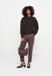 Brązowy sweter z dzianiny, taupe spodnie, czarne buty na obcasie i bordowa skórzana torebka na ramię. Teksturowane materiały i luźny krój.