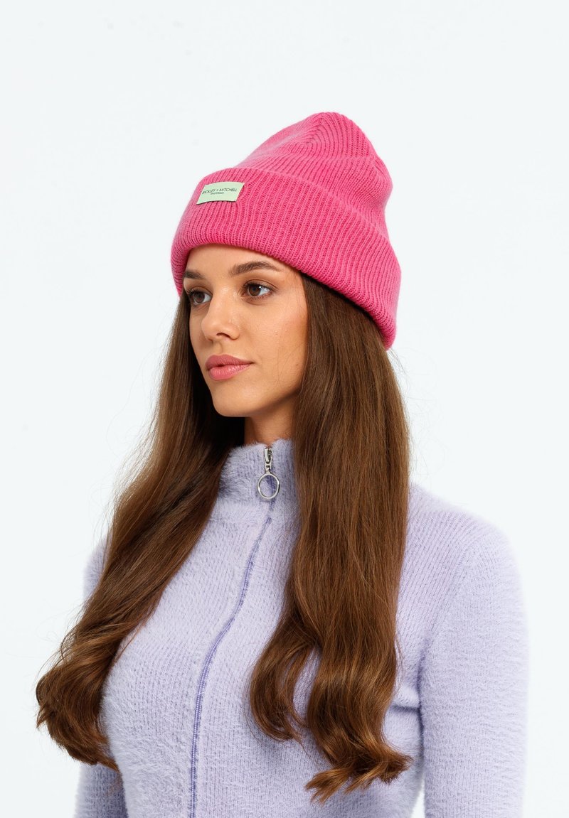Roze gebreide beanie met ribbeltextuur en een klein label. Gekocht met een lichtpaarse ritstrui met een fuzzy textuur.