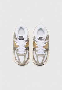 Nike Vomero 5 tenisice s mrežastim i sintetičkim gornjim dijelom, u kombinaciji bijele, zlatne i sive boje. Debeli bijeli vezice i podstavljena ivičnjaka.