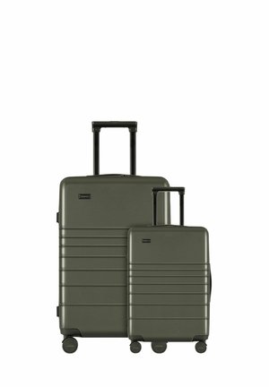 Ensemble de valises rigides vertes avec une surface texturée, comprenant une grande valise et un petit bagage à main, dotés de poignées rétractables et de roues pivotantes.
