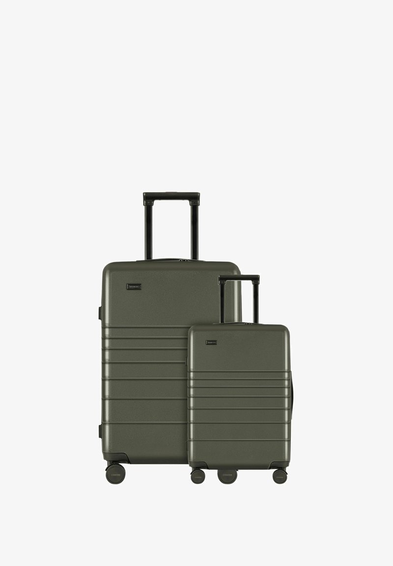 Ensemble de valises rigides vertes avec une surface texturée, comprenant une grande valise et un petit bagage à main, dotés de poignées rétractables et de roues pivotantes.