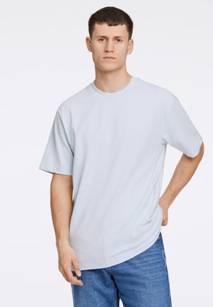 Lichtblauw, kortärmige T-shirt gemaakt van zacht stof, met een ronde hals en een relaxte pasvorm, gecombineerd met blauwe denim jeans.