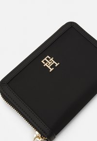 Mustvalge kaarditasku, mis on valmistatud tekstuurse materjaliga, esiküljel kuldne logo ja kuldsete tõmblukkudetailidega. Reservvormiga, mille servad on õmmeldud.