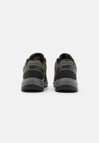 Zielono-czarne buty trekkingowe wykonane z siateczkowych i syntetycznych materiałów, z solidnymi szarymi podeszwami i odblaskowymi akcentami na pięcie.