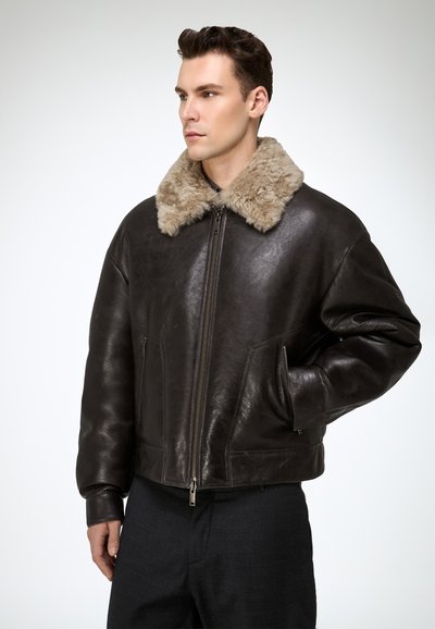 Brown leather bomber jacket with a plush beige fur collar, zip front, and side pockets, featuring a relaxed fit and smooth texture.