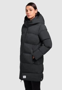 Black puffer coat with a hood, horizontal quilted design, zippered pockets, and logo patch on the lower front, offering a warm and fitted silhouette.