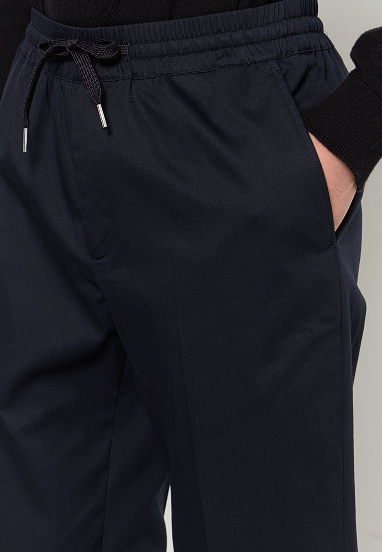 Marineblaue Hose mit elastischem Bund und Kordelzug. Verfügt über Seitentaschen und eine glatte Textur für Komfort.