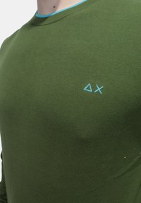 Maglietta verde a maniche lunghe con colletto girocollo, caratterizzata da un colletto azzurro e un logo ricamato in azzurro sul petto.