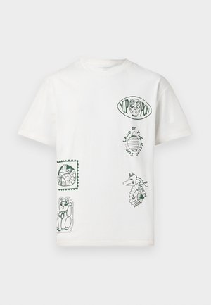 T-shirt en coton blanc avec des graphismes imprimés verts, comprenant des motifs animaliers et des éléments textuels, disposés en différentes positions et tailles.