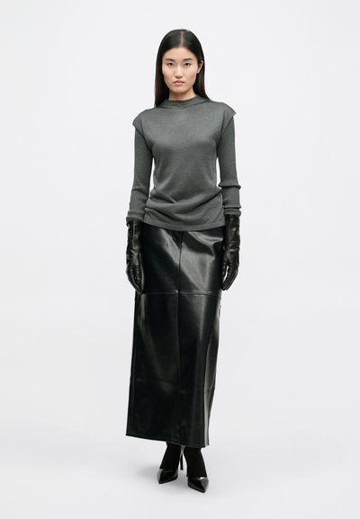 Szürke, hosszú ujjú felső, texturált anyagból, fekete bőrnadrággal párosítva. Kiegészítők között fényes fekete kesztyűk és hegyes sarkú cipők találhatók.