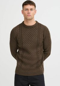 Brauner gestrickter Pullover mit Zopfmuster, geripptem Rundhalsausschnitt und strukturierten Details auf der Vorderseite und den Ärmeln.