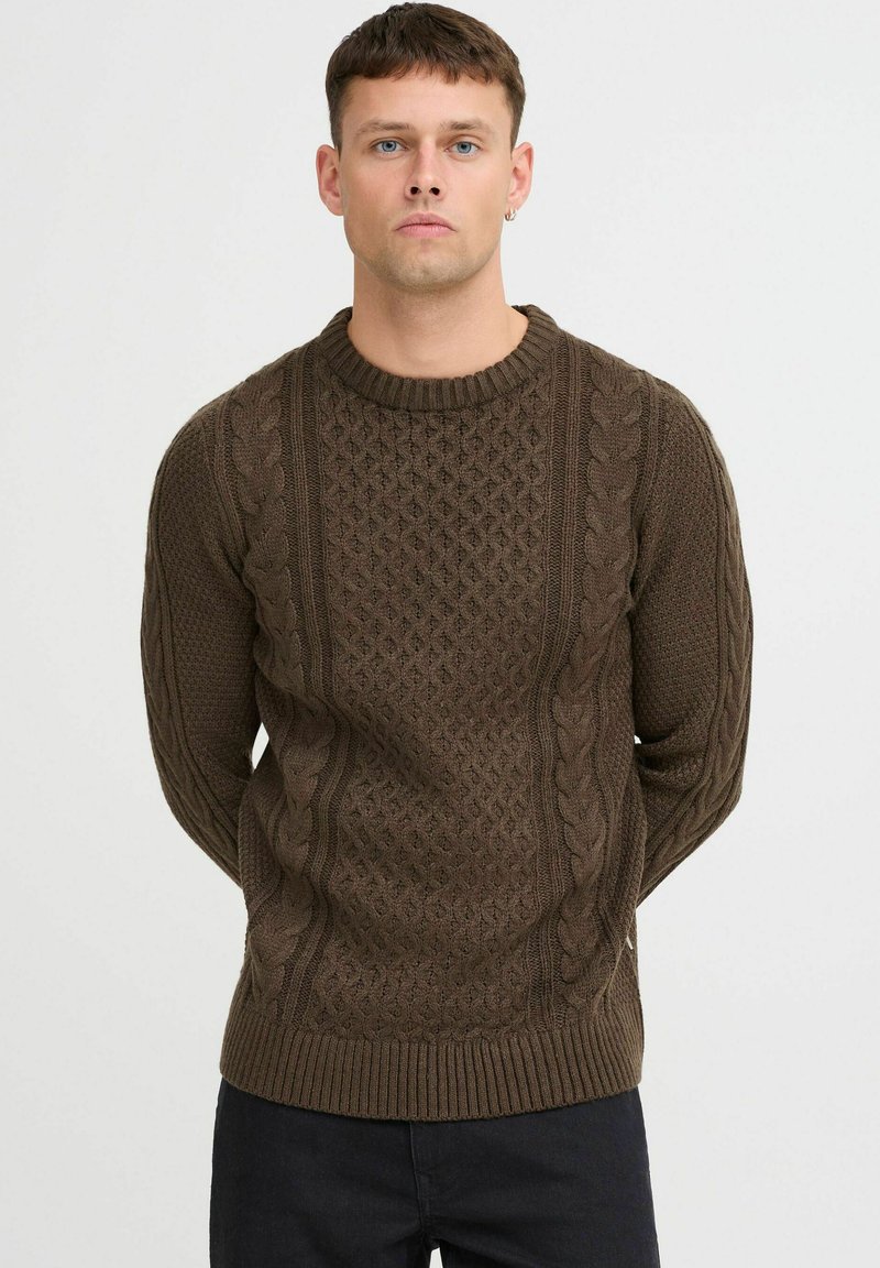 Brauner gestrickter Pullover mit Zopfmuster, geripptem Rundhalsausschnitt und strukturierten Details auf der Vorderseite und den Ärmeln.