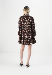 Robe noire froncée avec un imprimé animal coloré, manches longues bouffantes et ourlet évasé. Tissu lisse avec une texture douce.