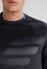 Černá sportovní mikina s texturovanou látkou, kulatým výstřihem a vrstveným designem s matně šedými akcentovými pruhy.