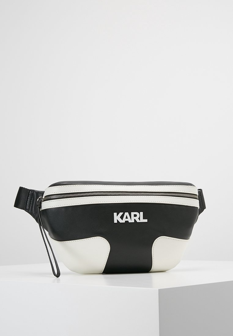 Mustekka ja valkoinen vyölaukku vetoketjulla, jossa on sileä pinta, kontrastivalkoiset yksityiskohdat ja logo "KARL" valkoisena.