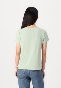 Lysegrønn bomulls T-skjorte med korte ermer, rund hals og ensfarget bak, kombinert med blå high-waisted jeans.