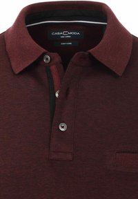 Bordeaux poloshirt met een gestructureerde weefwijze, een zwarte streep onder de kraag en zilveren knoopaccenten. Maatlabel: Groot, Eenvoudig onderhoud.