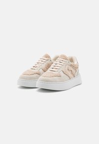 Krémové tenisky s texturovaným béžovým svrškem, doplněné měkkým akcentem, bílou podrážkou a tradičním šněrováním.