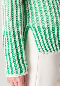 Strickpullover mit grün-weißer Streifenmuster, aus strukturiertem Garn, lockerer Passform und seitlichem Schlitz am Saum.