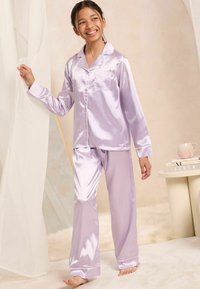 Conjunto de pijama de satén lila que incluye una camisa de botones de manga larga con bolsillo y pantalones a juego; textura suave y diseño clásico.