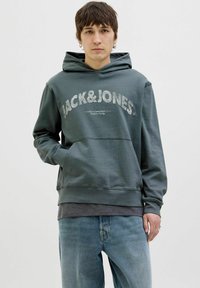 Zelena dukserica s kengurskom džepom, s natpisom "JACK&JONES". Izrađena od mekog materijala, završena kapuljačom sa vezicom i rebrastim manžetama.